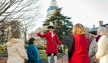Period-attired guide with group by the Maryland State House.